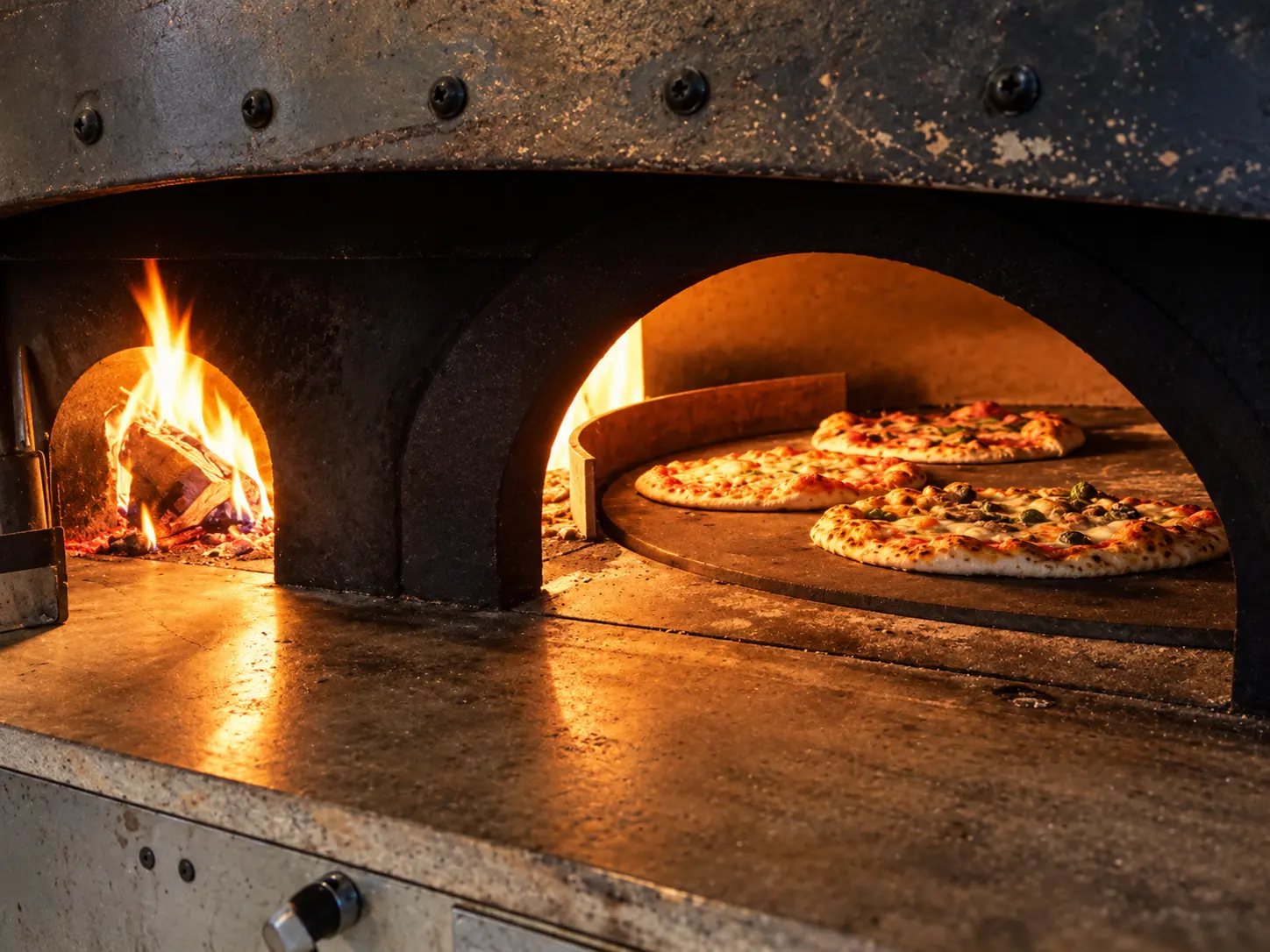 Brennender Holzofen mit frisch gebackenen Pizzen